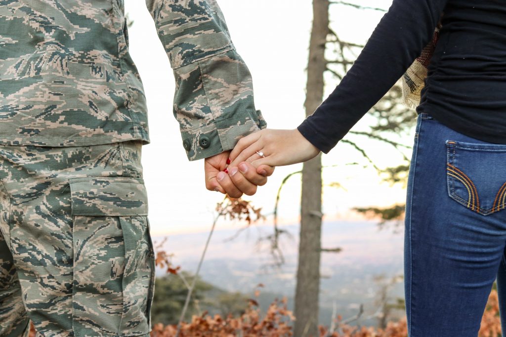 soldier holding hands with woman, no faces visible