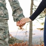 soldier holding hands with woman, no faces visible